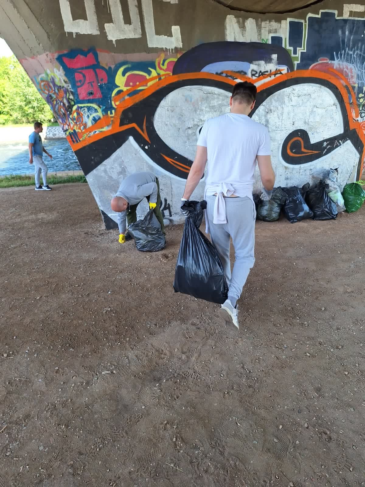 Član organizacije RED nosi vreću prikupljenog otpada ispod mosta na Niškom keju